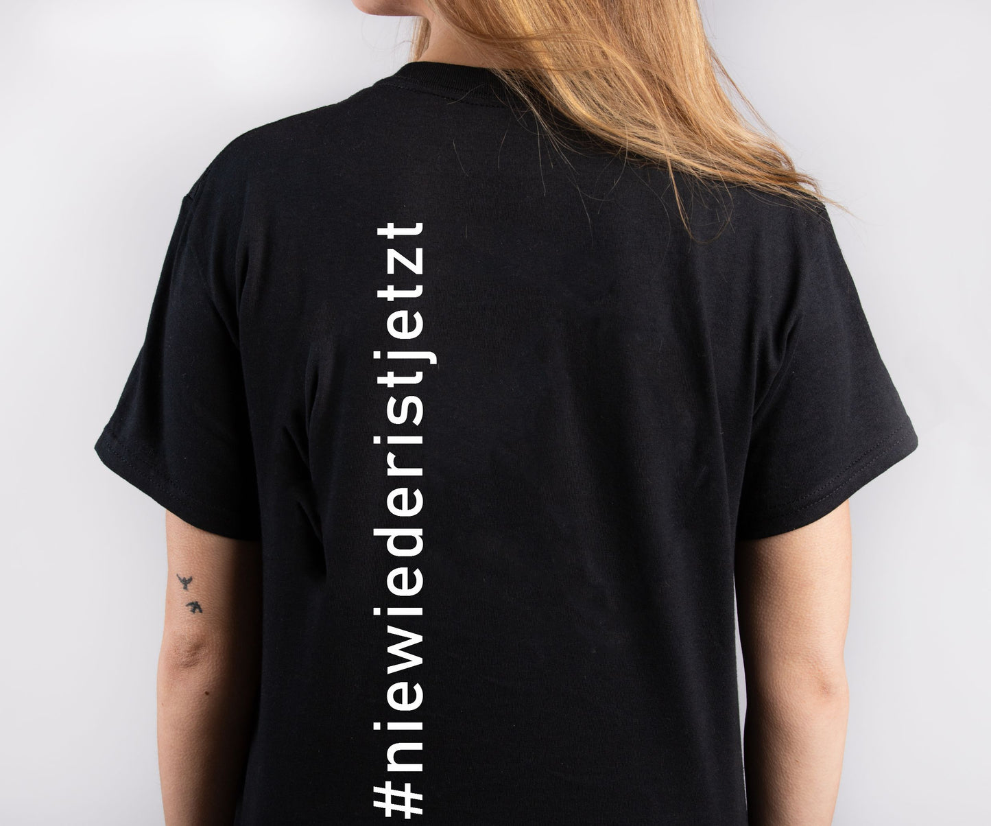 schwarzes Unisex-T-Shirt mit dem weißen Frontprint „Nie wieder ist jetzt“. Das Shirt besteht aus Bio-Baumwolle und wird im hochwertigen Siebdruckverfahren veredelt – ein sichtbares Statement gegen Faschismus und für Erinnerungskultur.