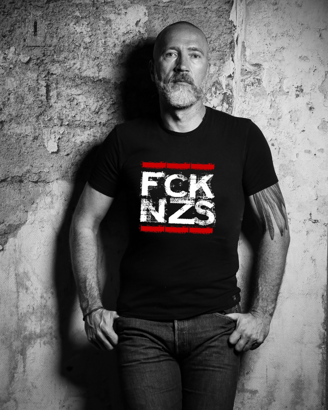 Mann trägt schwarzes Unisex Statement-T-Shirt FCK NZS – Gildan Heavy mit Frontprint gegen rechte Ideologien, 100 % Baumwolle, gerader Schnitt, politisches Shirt für Vielfalt und Toleranz