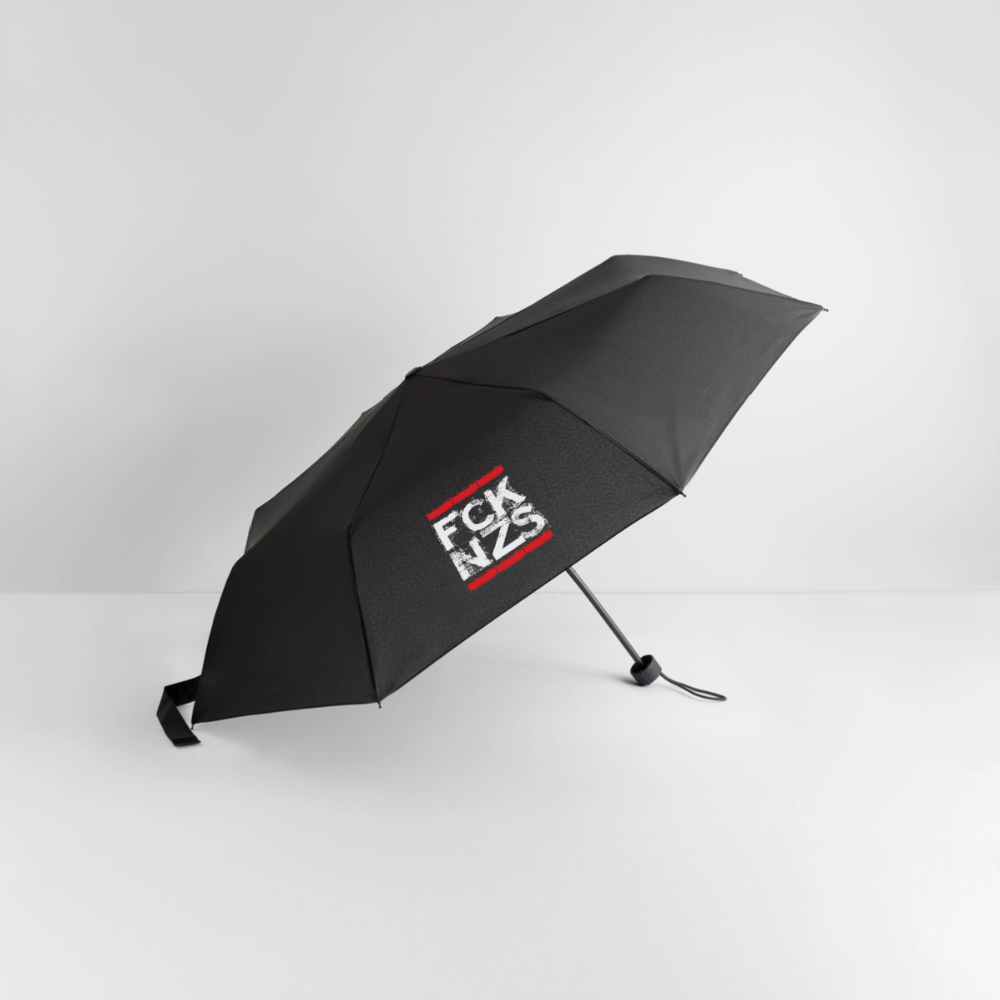 Schwarzer Faltregenschirm mit weißem „FCK NZS“ Print im roten Rahmen. Kompakt, mit Klettverschluss und Schutzhülle. Statement gegen Faschismus.