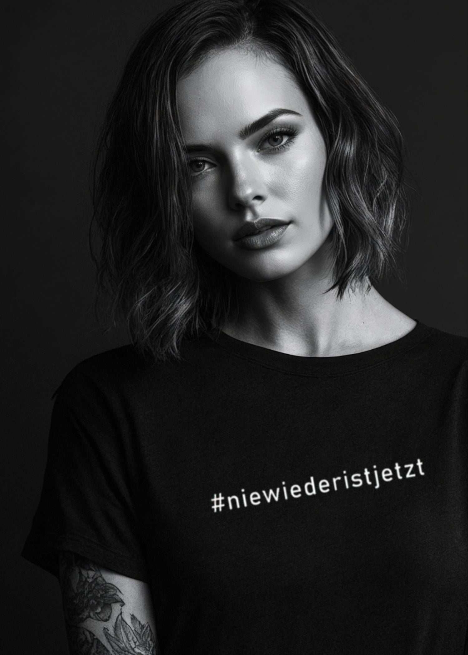 Unisex-T-Shirt mit dem Aufdruck „Nie wieder ist jetzt“, fair produziert aus Bio-Baumwolle, in Schwarz oder Weiß. Hochwertiger Siebdruck auf Vorder- und Rückseite – getragen von einer Person mit neutralem Hintergrund.